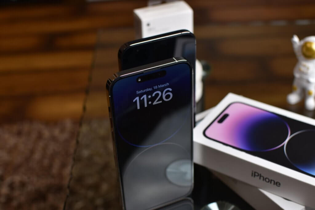 Deux iPhone 14 posés sur une table avec écrans allumés.